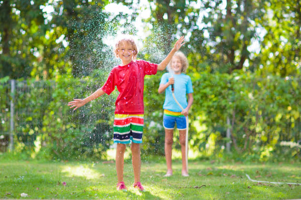 istock Kids play with water sprinkle hose. Summer garden 1483499406
