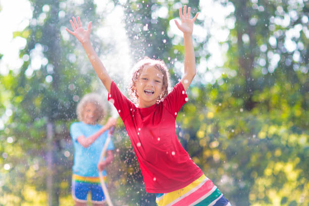 istock Kids play with water sprinkle hose. Summer garden 1483501151