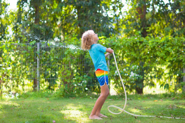 istock Kids play with water sprinkle hose. Summer garden 1483502180