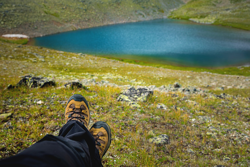 Traveler resting on a mountain plateau. POV view, legs close up on the background of mountain landscape.