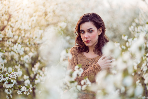Spring portrait of beautiful young woman in blossoming orchard.
