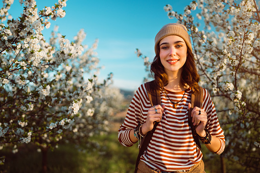 Spring portrait of beautiful young woman standing in blossoming orchard.