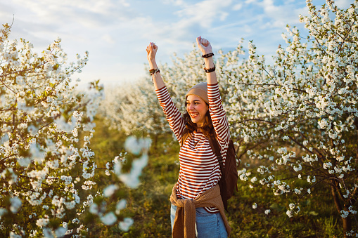 Spring portrait of beautiful happy young woman in blossoming orchard.