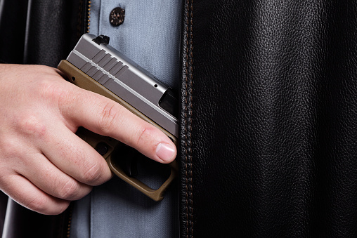 An automatic pistol being drawn from a man's jacket.