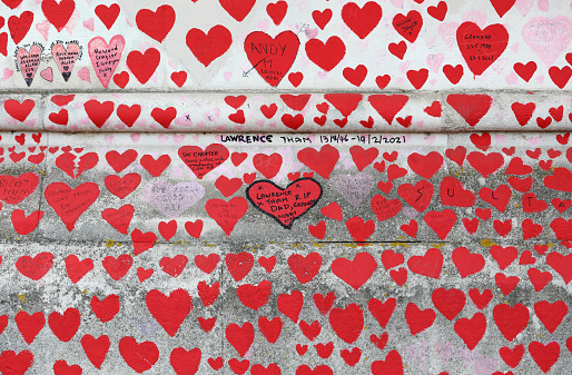 London, United Kingdom - September 18 2022: Red hearts painted in memory of people who have died of Covid-19 during the coronavirus pandemic at the National Covid Memorial Wall in London, United Kingdom. The wall is a place for people to come to reflect or to write messages or the names of lost loved ones.