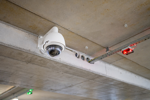 Low angle view of surveillance camera in underground parking space.
