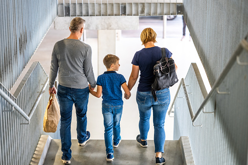 Family holding hands while walking on staircase.