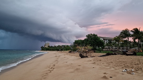 A scenic beach landscape featuring a cloudy sky filled with dark storm clouds in Kaanapali beach, Maui