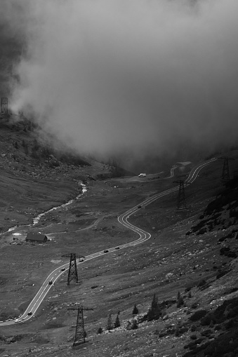 Aerial grayscale of the majestic fog-covered mountains and winding Transfagarasan road