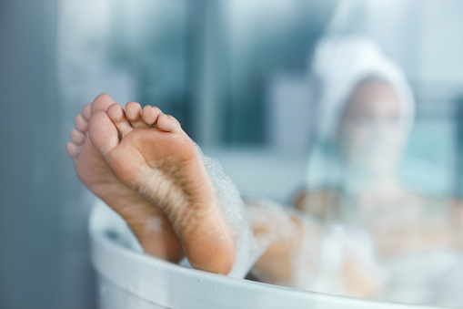 Close up of unrecognizable woman relaxing during her bubble bath in a bathroom.