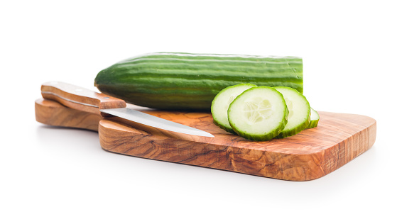Sliced fresh green cucumber on cutting board isolated on the white background.