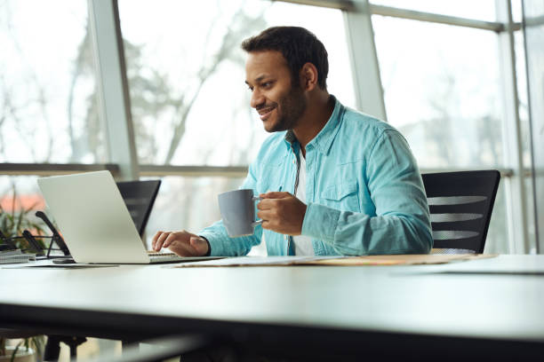 istock Smiling male using laptop and drink tea 1483526564