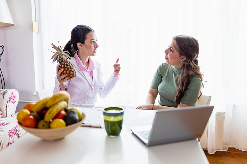 A nutritionist in her clinic helps her patient achieve weight loss goals through personalized meal planning and lifestyle changes