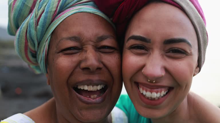 Close up of happy african mother and daughter wearing traditional afro dress while smiling in front of camera