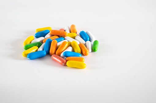 Delicious colored sweet licorice candies in capsules or pills on a white background, overhead view.