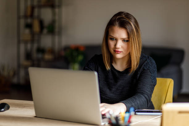 istock Diligent young woman sitting at her desk, typing data on laptop 1483531527