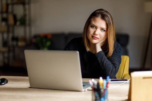 istock Diligent young woman sitting at her desk, typing data on laptop 1483531530