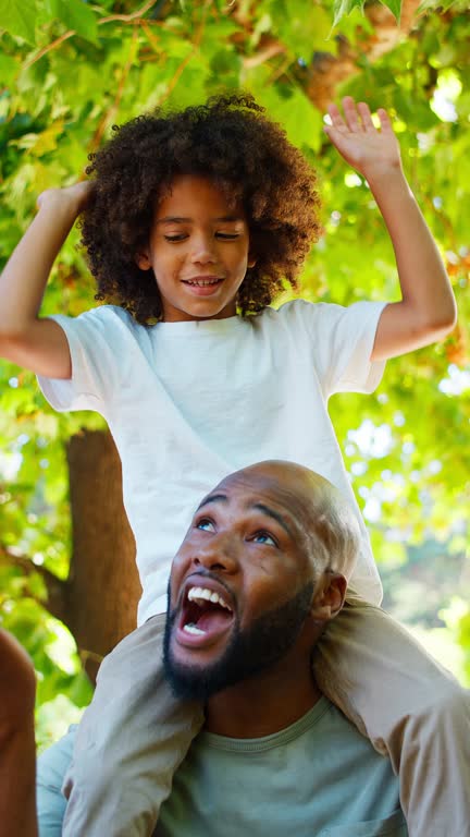 Vertical Video Of Father And Son In Summer Garden With Boy Riding On Dads Shoulders