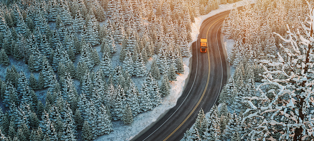 Truck driving on the highway through a forest full of trees winter covered with snow.3 d renderings and illustrations.
