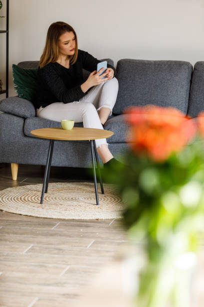 istock Young woman relaxing on the sofa after work and using smart phone to pass time 1483532357