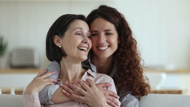 Cheerful pretty adult daughter woman hugging mature 50s mom