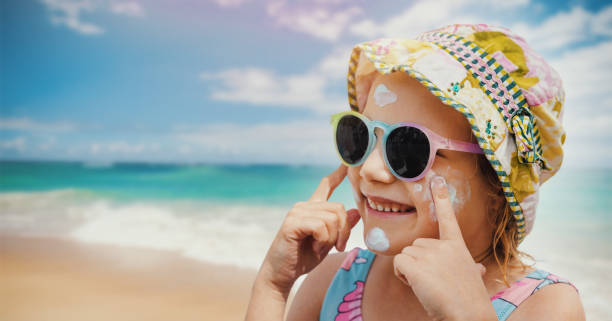 child put on sunscreen on face at beach. skin protection from sunburn. banner with copy space stock photo