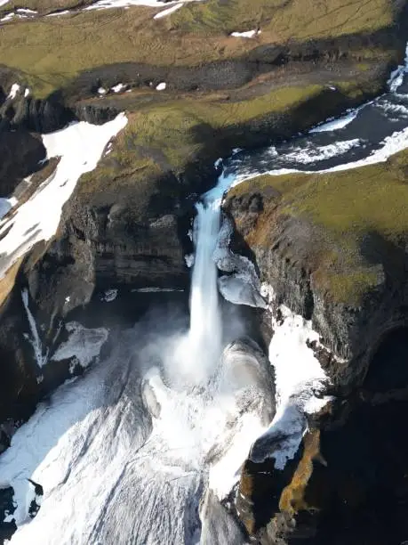 An aerial view of the majestic Haifoss Waterfall, Iceland cascading down a snow-covered mountainside