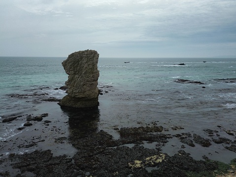 A stunning landscape featuring a large rock formation jutting out of the ocean