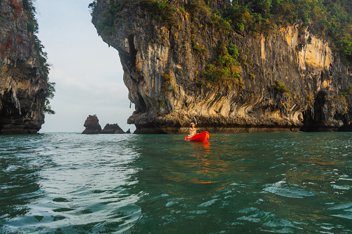 Young Caucasian woman in swimsuit  sea kayaking near idyllic Railey beach  in Thailand