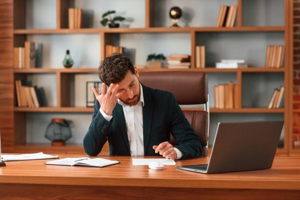 istock Tired, feeling bad. Businessman in formal clothes is working indoors 1483542521