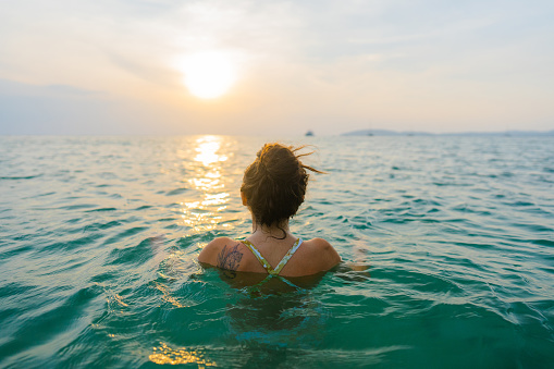 Young  woman swimming at sunset in Andaman sea