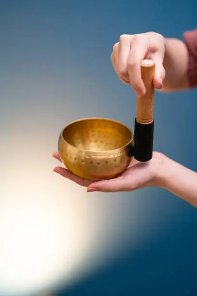 Woman hands holding a Tibetan singing bowl and playin.