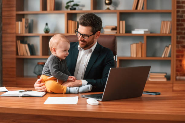 With toddler. Businessman in formal clothes is working indoors stock photo