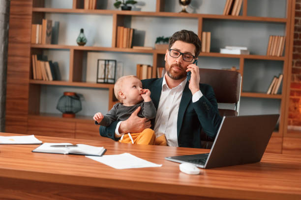 istock Conception of multitasks. Businessman in formal clothes is working indoors. With toddler 1483543532