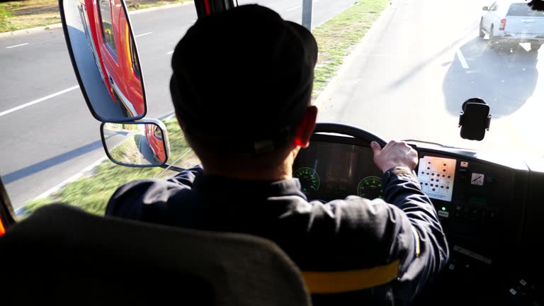 Young fireguard holds hands on steering wheel and controls a car riding to the place of fire. Fireman operating the fire car on urban road. Male firefighter driving on fire engine to an emergency