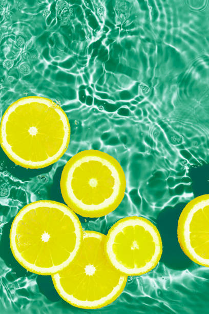 istock Creative summer composition made of sliced lemon in green transparent water. Refreshment concept. Healthy refreshing drink theme. Top view 1483550583