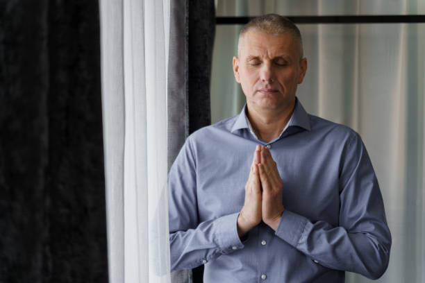 istock A man stands near the window doing relaxing breathing exercises. 1483551938