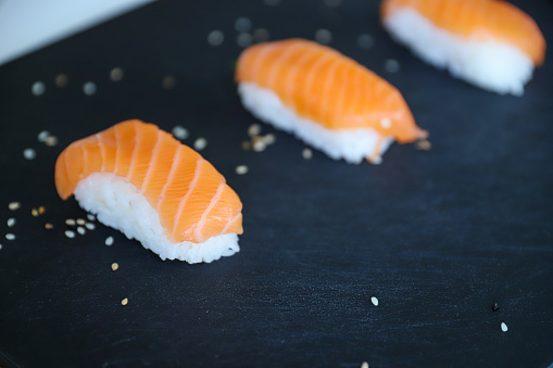 a close up of nigiri sushis on dark tray