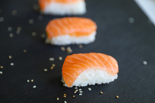 a close up of nigiri sushis on dark tray