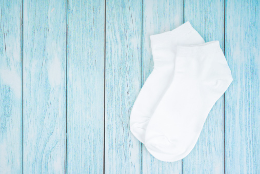 White cotton socks for design on blue wooden background with copy-space.