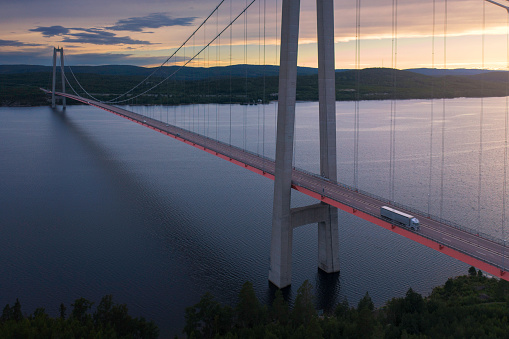 A truck on the the 1 867 metres long High Coast Bridge (Högakustenbron) on the east coast of Sweden on a summer evening at sunset.