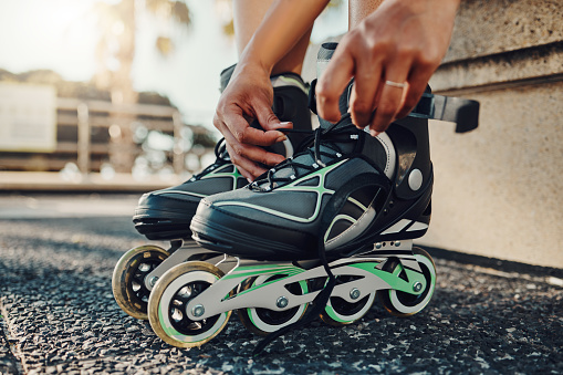 Hands, fitness and tie roller skates in city to start workout, health and wellness exercise. Sports practice, training and black woman skater tying shoes in street to get ready for skating outdoors.