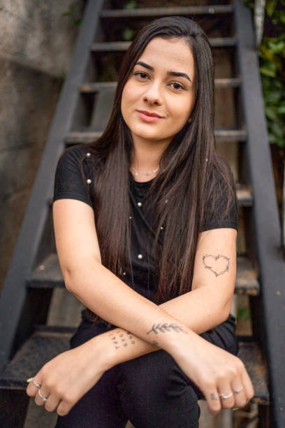 istock Smiling young woman with tattoos sitting outside on steps 1483566404