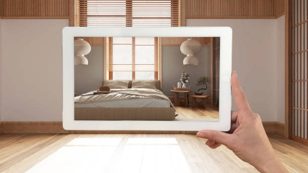 istock Augmented reality concept. Hand holding tablet with AR application used to simulate furniture and design products in empty interior with parquet floor, japandi bedroom 1483567268