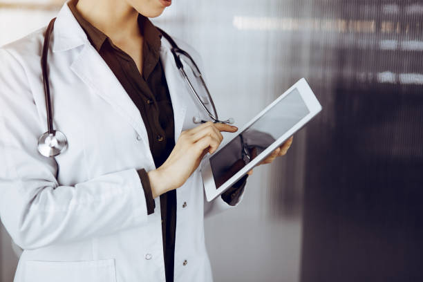 istock Unknown female doctor using tablet computer in sunny clinic. Medicine concept 1483569877