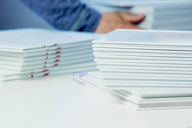 istock stack of freshly printed photobooks on the table close-up, blurry hands visible in the background 1483571567