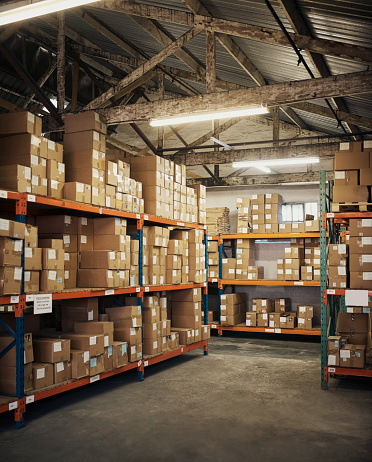 Factory, empty warehouse and boxes for delivery, courier and shipping logistics in storage. Backgrounds, stock and commercial package on shelf for manufacturing, supply chain industry or distribution