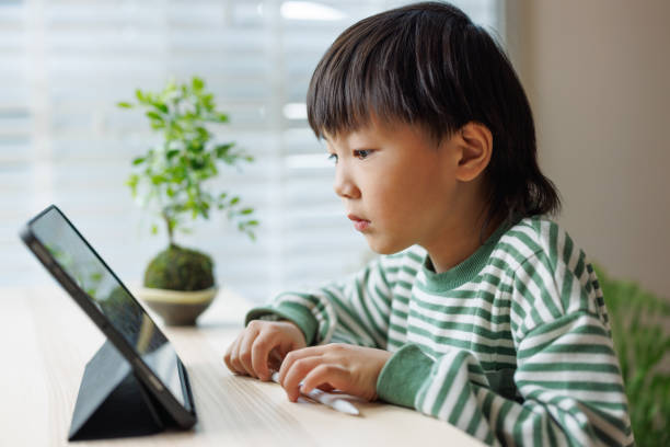 istock An Asian boy is watching videos at home using a digital tablet 1483572254