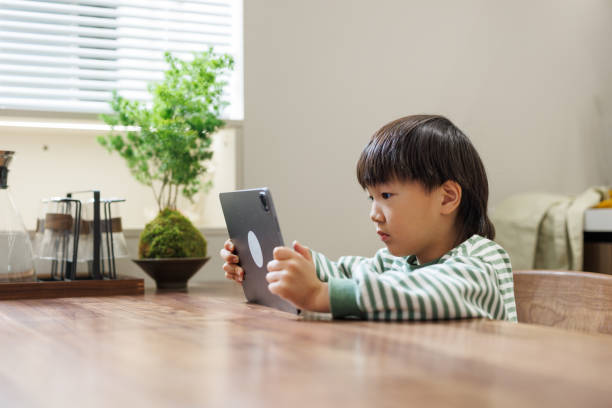 istock Asian Boy Watching Videos on a Digital Tablet in a dining room 1483572262
