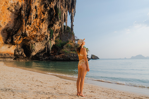 Young Caucasian woman  walking on Railey beach and looking at stunning scenery